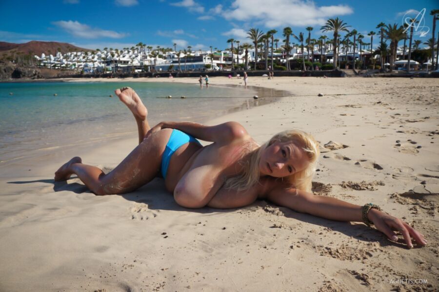 Sexy Blondine mit riesigen Titten oben ohne am Strand