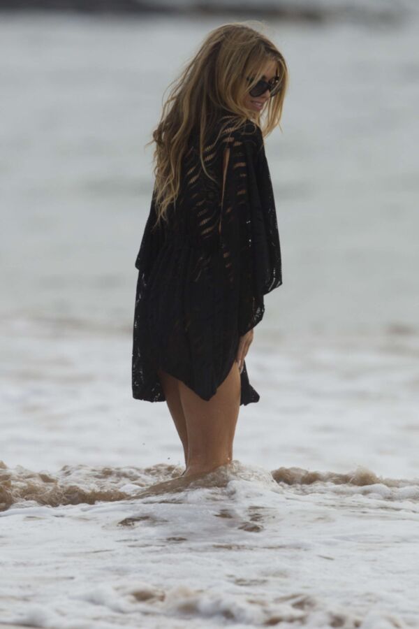 Carmen Electra à la plage se roulant dans le sable