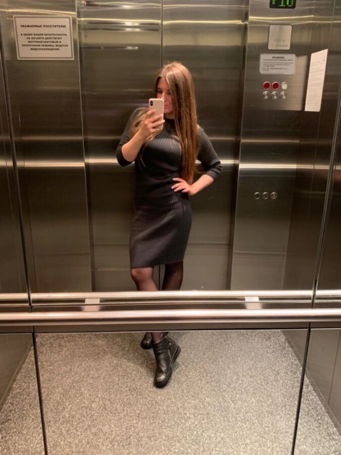 Sexy Büroschlampe in schwarzen Strumpfhosen macht ein Selfie im Aufzug