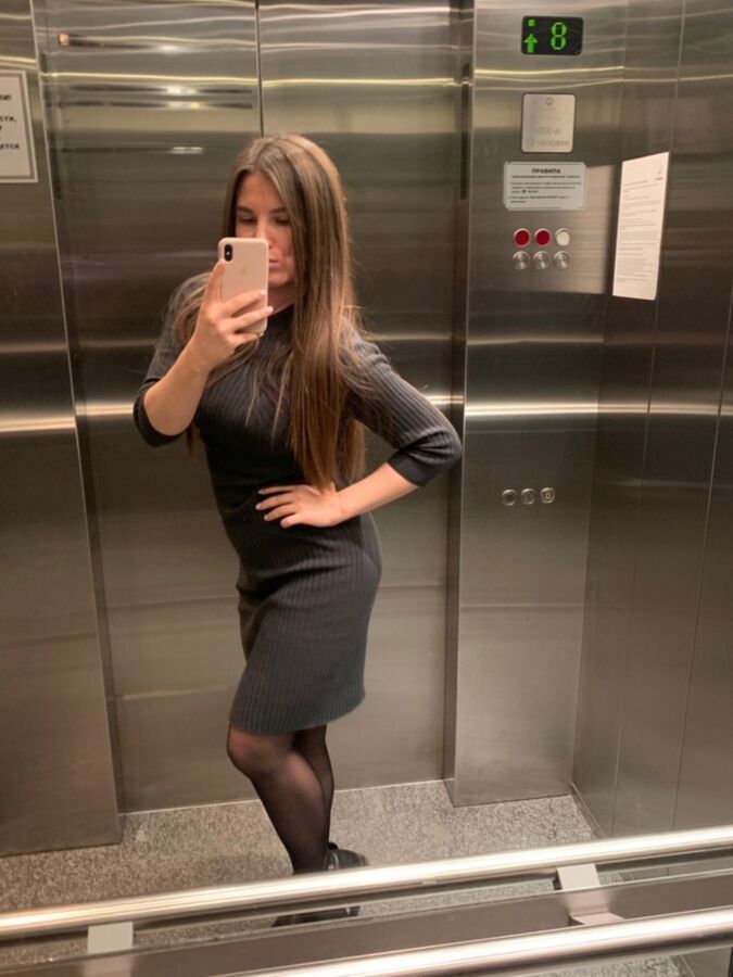 Sexy Büroschlampe in schwarzen Strumpfhosen macht ein Selfie im Aufzug