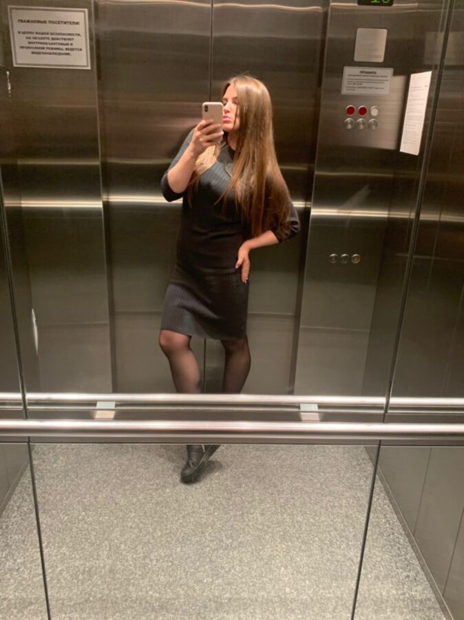 Sexy Büroschlampe in schwarzen Strumpfhosen macht ein Selfie im Aufzug