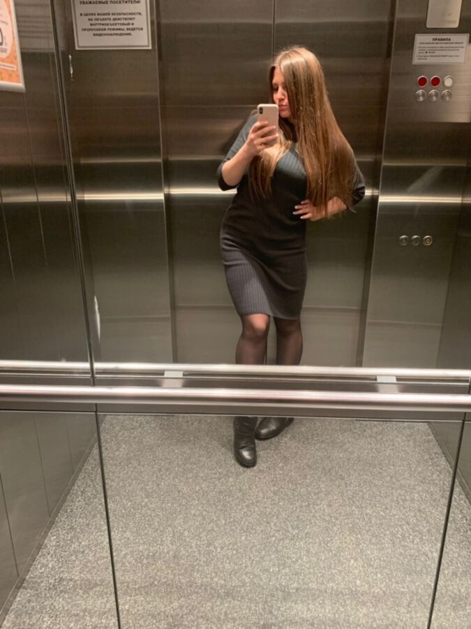 Sexy Büroschlampe in schwarzen Strumpfhosen macht ein Selfie im Aufzug