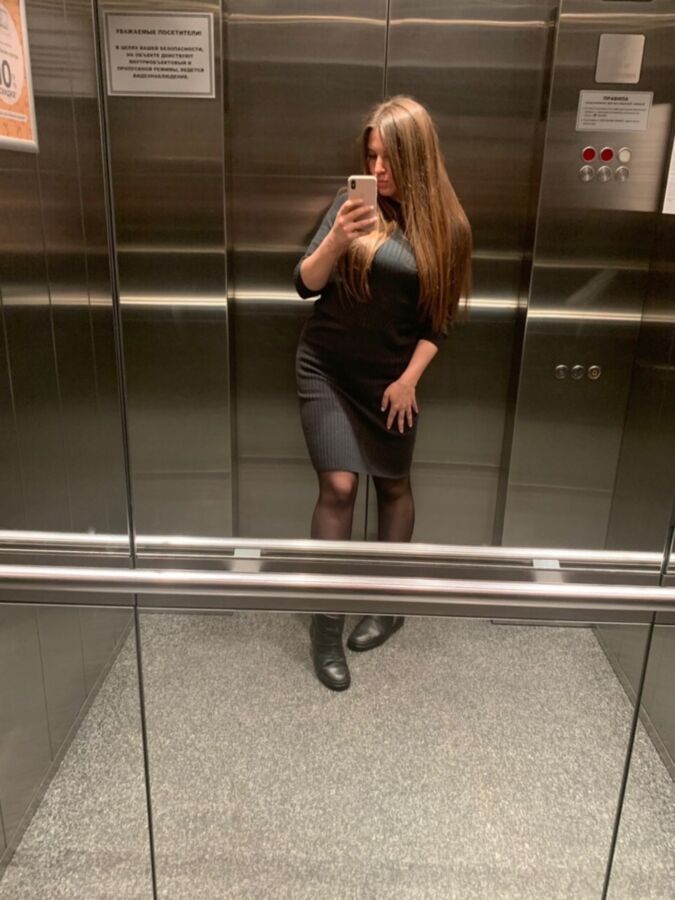 Sexy Büroschlampe in schwarzen Strumpfhosen macht ein Selfie im Aufzug