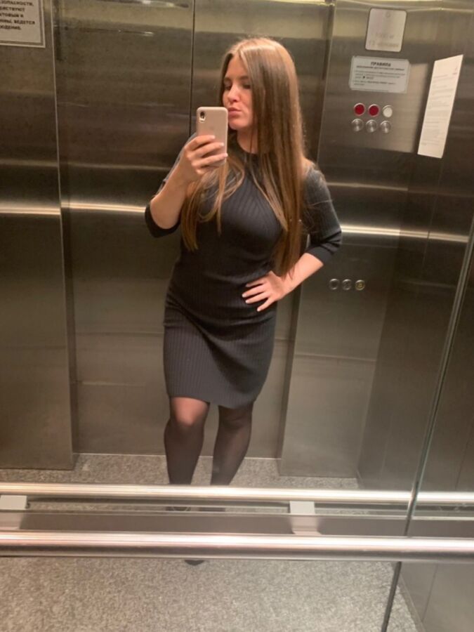 Sexy Büroschlampe in schwarzen Strumpfhosen macht ein Selfie im Aufzug