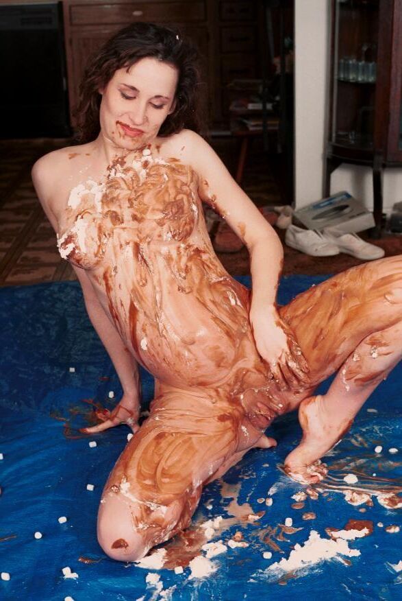 Pregnant brunette smears herself with chocolate pudding