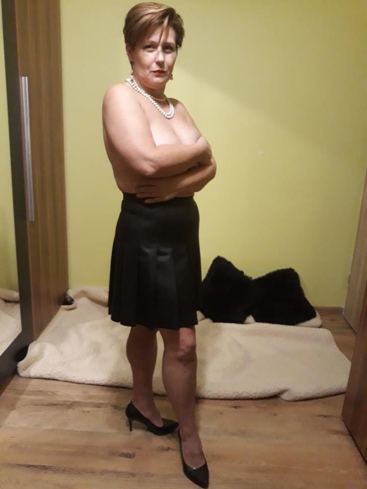 Esposa caliente solo con minifalda negra, tacones y collar de perlas