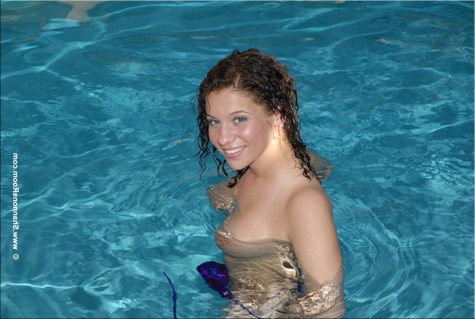 Ellie Busty Babe in einem aufschlussreichen lila Bikini wird oben ohne